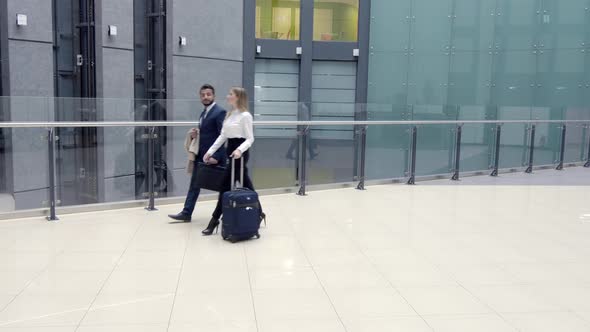 Businessman and woman going inside building along glass fence