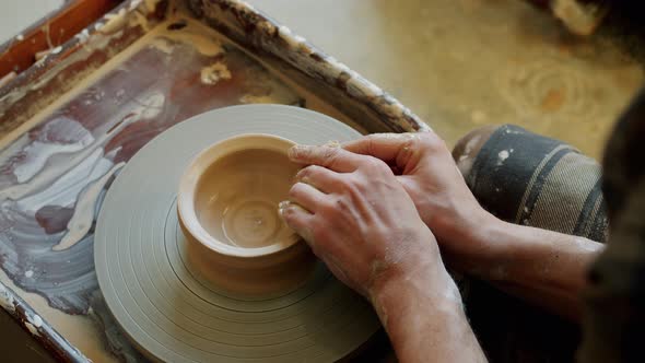 Close-up of Young Man's Hands Molding Clay Into Ceramic Bowl on Throwing Wheel alt