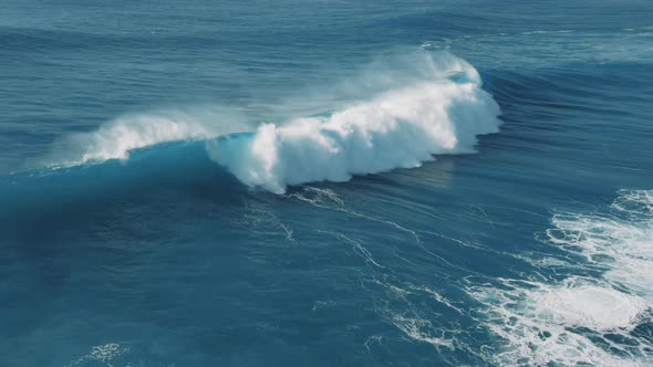 Aerial view of curling ocean waves with splashing wave crest
