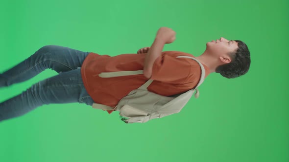 Asian Boy Student Wearing A Backpack, Running To School On Green Screen alt