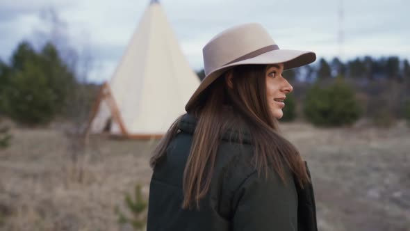 Young Beautiful Smiling Woman Walking Through Field Towards Teepee On Spring Winter Autumn Glamping