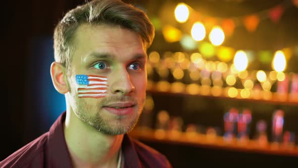 Nervous American Soccer Fan With Flag on Cheek Unhappy With Game Result alt