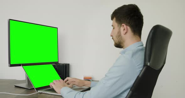 Boy in Blue Shirt in a Modern Office Typing on Computer alt