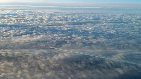 Incredible view from the cockpit of an airplane flying high above the clouds leaving a long white co alt