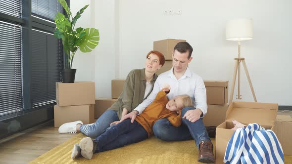 Happy Beautiful Family Relaxing on Floor While Moving Into New House