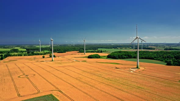 Aerial view of wind turbines and golden field near highway. alt
