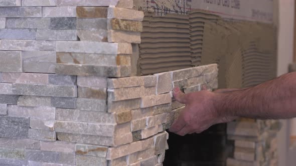 Male Worker Hands Setting Stacked Stone Tiles for Fireplace alt
