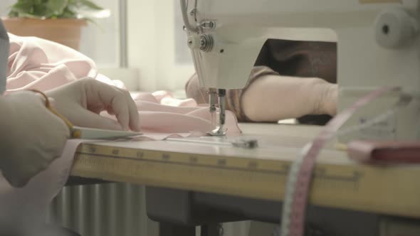 Cutting a pink fabric near a sewing machine alt