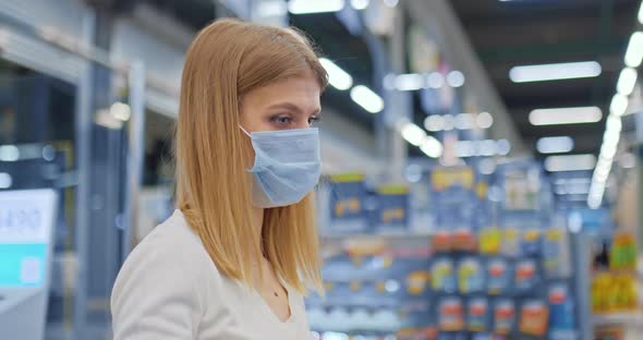 Portrait a Beautiful Girl in a Medical Mask Pays for Purchases By Phone alt