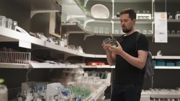 A Young Man is Looking for Glassware for His Stylish Apartment alt