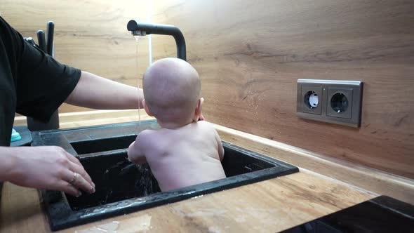 Baby in Kitchen Sink Bathing and Playing with Water