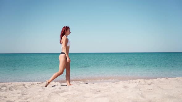 Beautiful Girl in Swimsuit Walking Along Transparent Turquoise Sea Along Coast alt