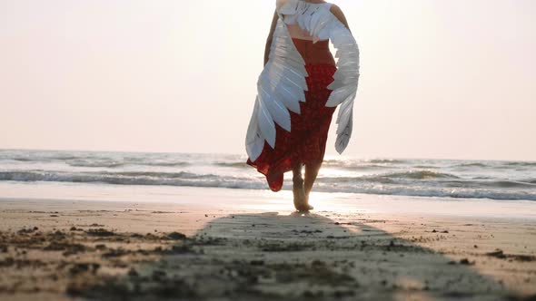 Beautiful Female Angel Walking Barefoot Toward the Sea at Sunset