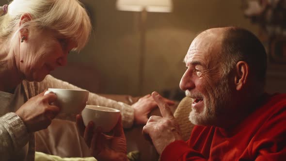 Elderly Couple with Tea Speaking in Living Room alt