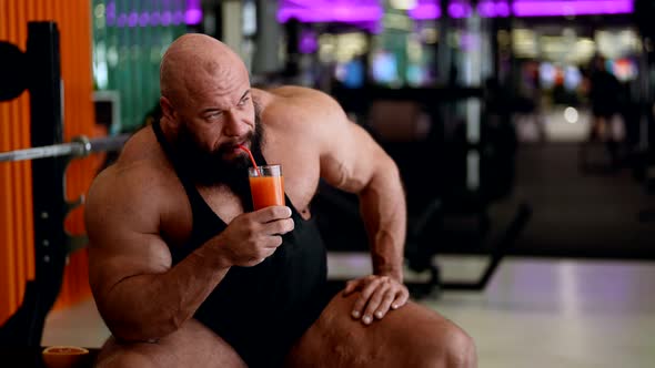 Sporty Man with Large Muscles is Resting in Gym and Drinking Vitamin Juice Cocktail Powerlifter alt