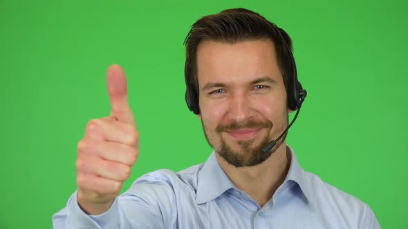 A Young Call Center Agent Shows a Thumb Up To the Camera and Smiles - Closeup - Green Screen Studio alt