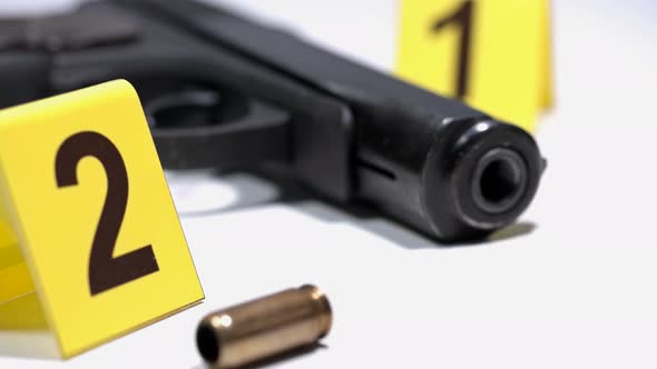 on the Crime Scene, on the Floor, Lay a Pistol and Shell Casing Marked with Photo Markers alt