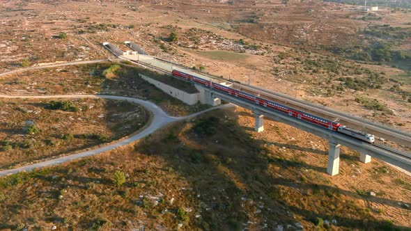 Train passing trough the tall bridges in the Judea valleys of Israel, aerial drone view alt