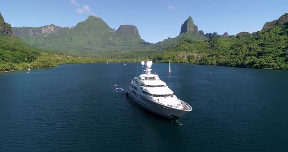Aerial views of yacht in French Polynesia, stunning backdrop with large mountain in background alt