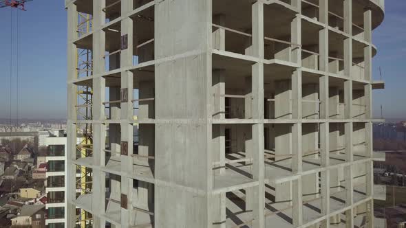 Aerial view of concrete frame of tall apartment building under construction in a city. alt