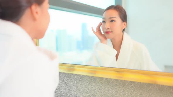 Young asian woman check her face on mirror alt