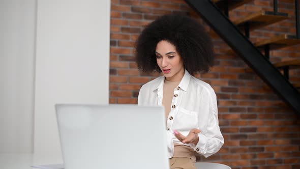 A Young Biracial Woman is Using a Laptop for Video Connection Indoor