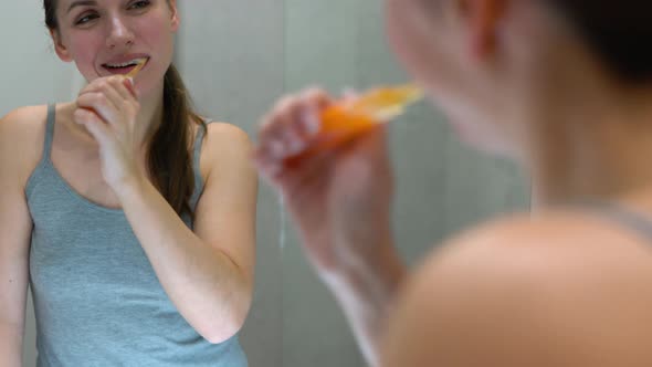 Pretty Woman Brushing Her Teeth in a Bathroom in the Morning alt