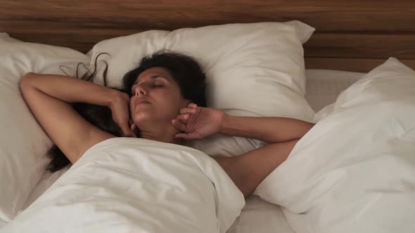 Young Woman is Sleeping in Her Bedroom at Sunny Morning Tossing and Turning