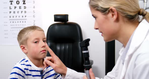 Female optometrist examining young patient with ophthalmoscope alt