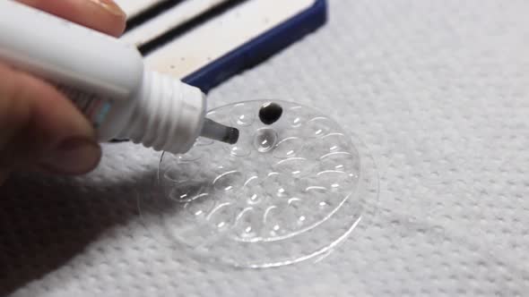 the Master Pours Eyelash Glue Into a Dish