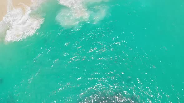 Aerial top down view of waves gently crashing on Kelingking Beach in Bali