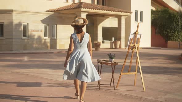 Wide Shot Back View of Gorgeous Slim Confident Woman Walking to Easel in Sunlight in Slow Motion alt