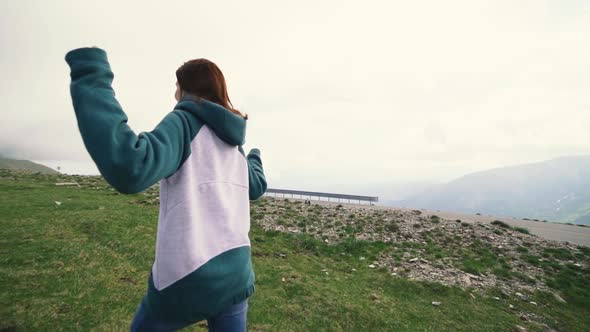 A Young Woman Hiker Running and Spinning on Top of a Mountain alt