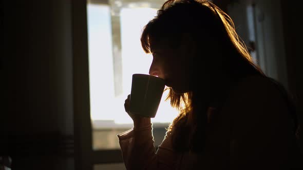 Silhouette of a Woman Drinking Coffee in the Sunset Sun Glare