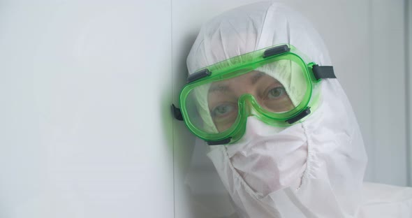 A doctor in protective clothing, a mask and goggles, close-up. Tired look. Antivirus suit
