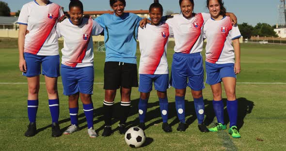 Female soccer team standing arm to arm on soccer field. 4k alt