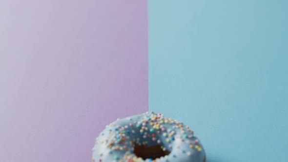 Video of donut with icing on purple and blue background alt