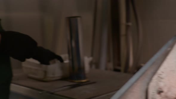 A Worker Places a Silver Bar and Metal Shavings in a Smelter at a Silver Factory alt