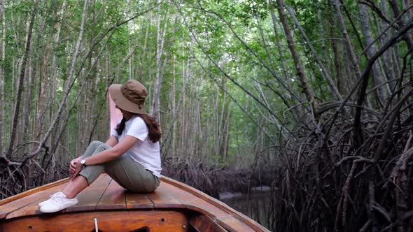 A beautiful young asian woman sitting on a long tail boat while traveling the mangrove forest