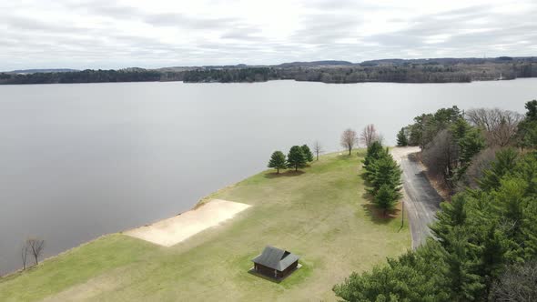 Aerial view of tranquil lake in midwest in fall. Park with small beach and shelter at edge of lake.