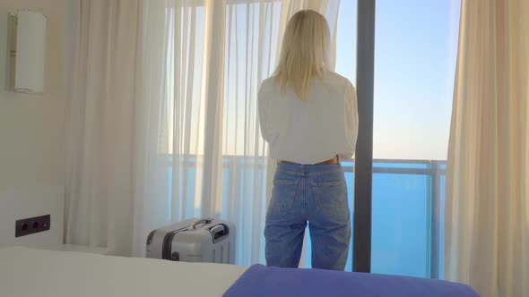 Portrait of tourist visiting hotel, standing at window and admiring beautiful alt