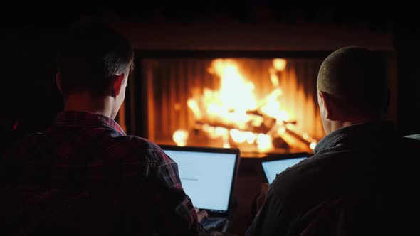 Winter Evening By the Fireplace - Men Use a Laptop and Tablet alt