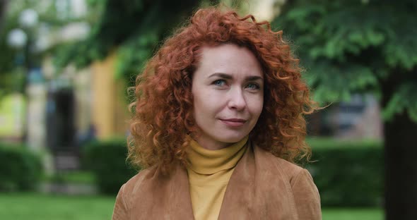 Attractive Red-haired Woman with Curly Hair Looks at the Camera and Says Something, Close Up Slow alt