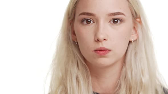 Young Attractive Blonde Caucasian Teenage Girl Smiling and Trying to Find Pimple on Nose on White alt