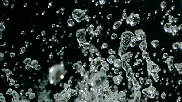 Water Droplets Rise in the Air Against Black Background. Slow Motion Water Splash on Black alt