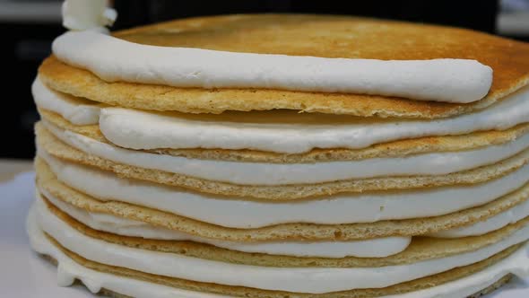 The Pastry Chef Squeezes a Layer of Cream Onto a Multilayered Sponge Cake alt