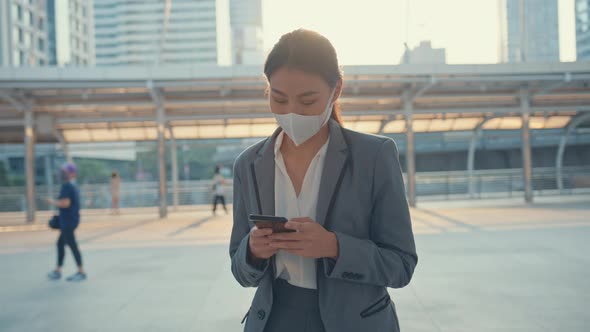 Young Asia businesswoman in fashion office clothes wear medical face mask using phone.