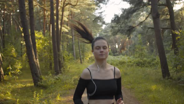 A Young Woman Runs Along a Forest Path and Goes in for Sports