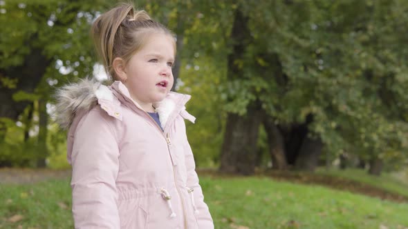 Cute Little Caucasian Girl Looks Around in a Park  Closeup alt