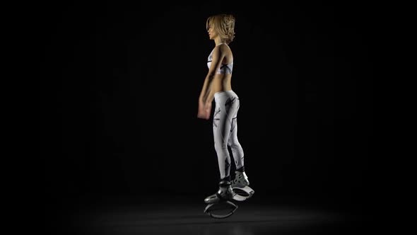 Athletic Girl Jumping in Kangoo Shoes Among Spotlights in Smoke on Black Background at Studio alt